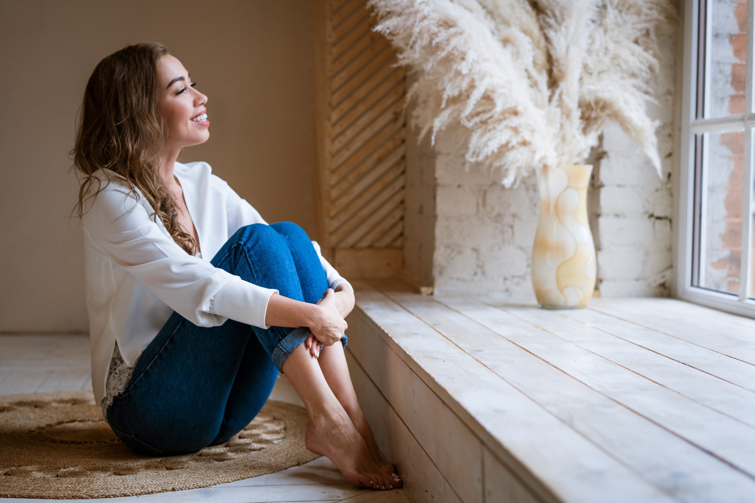 Woman sitting near a window with soft natural light — calm and reflective