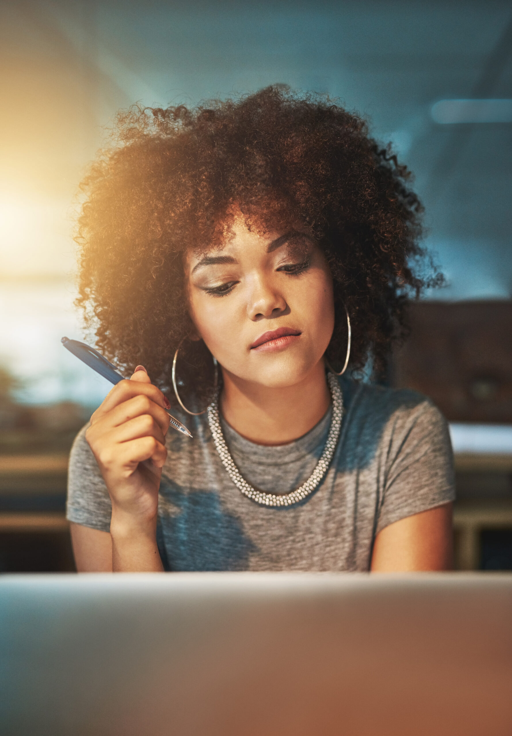 Woman journaling at a desk with soft light, thoughtful expression