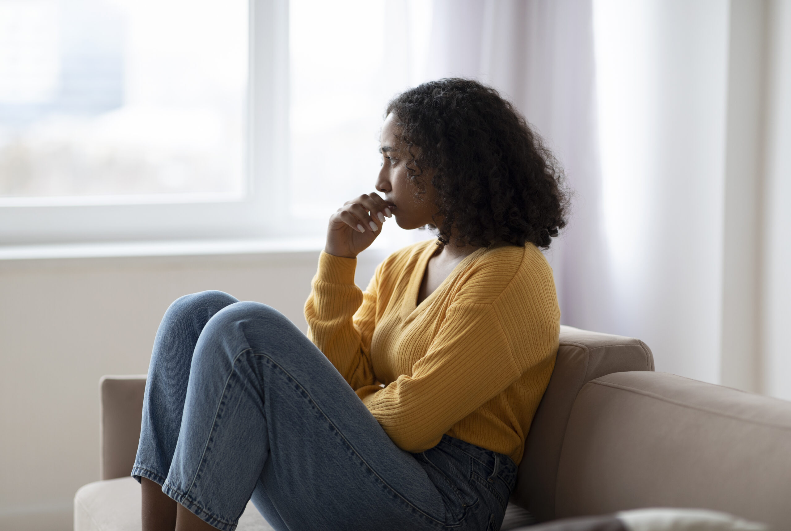 Woman sitting quietly in soft natural light — reflective and thoughtful expression